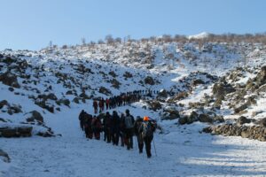 A large group of hikers traversing a snow-covered hill in Aksaray, Türkiye.